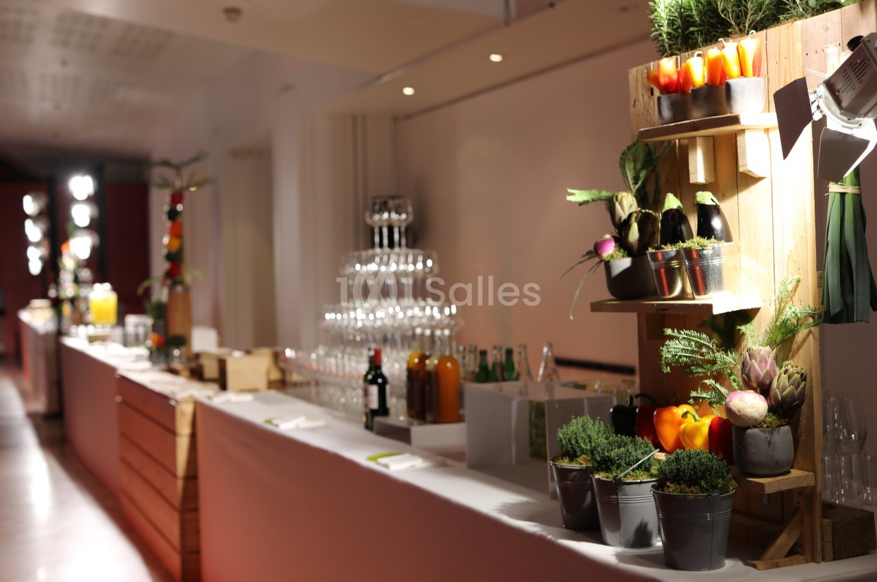 Table de buffet élégante avec verres empilés, boissons et décorations végétales sur des étagères en bois.