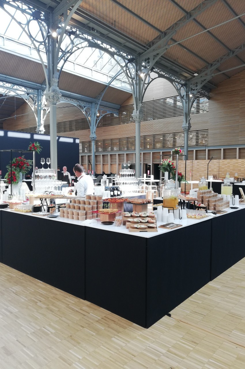 Buffet élégant avec boissons, viennoiseries et plats variés dans une grande salle lumineuse au style industriel.