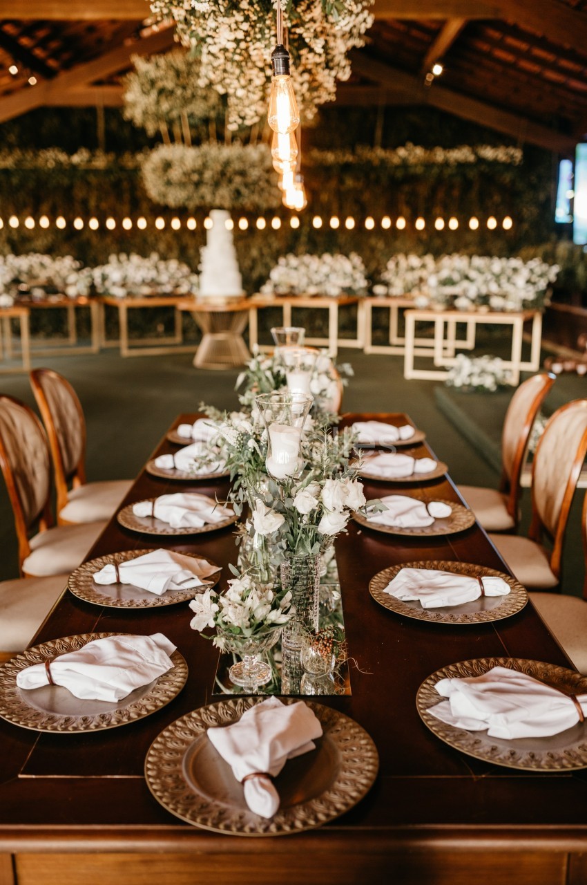 Table élégamment dressée avec des assiettes, serviettes pliées et décorations florales dans une salle ornée de guirlandes…