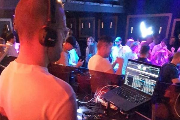 Un DJ mixe de la musique sur son ordinateur portable devant une foule dans une boîte de nuit.