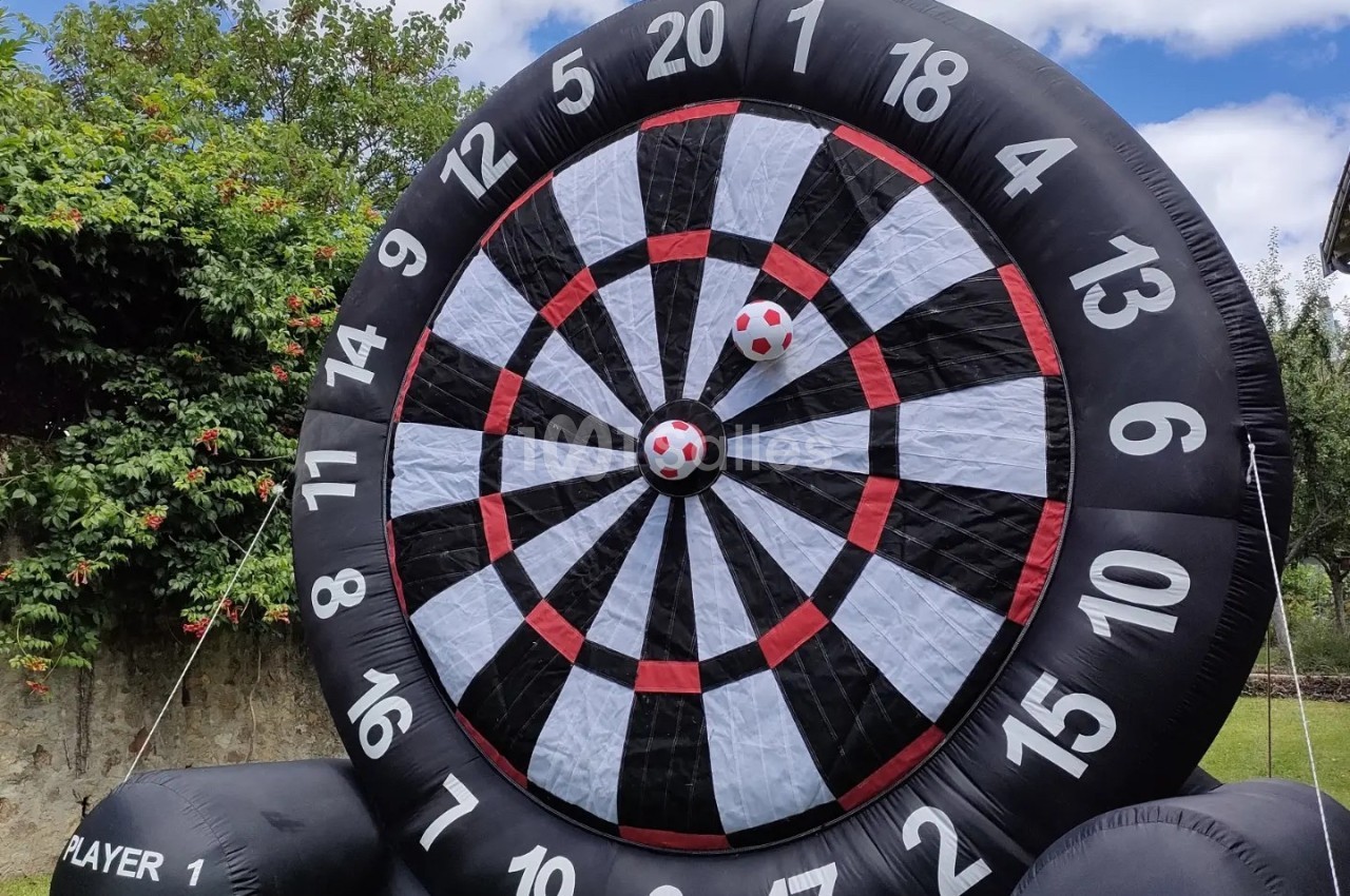 Cible géante gonflable en extérieur avec deux balles rouges et blanches fixées au centre.