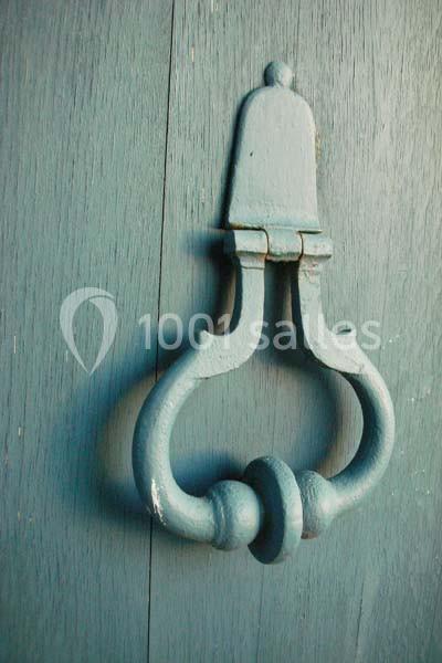 Heurtoir en métal de style ancien fixé sur une porte en bois peint en bleu.
