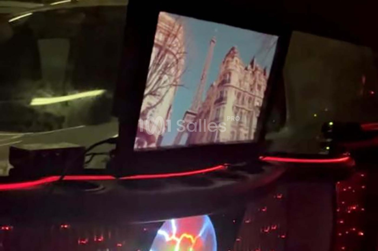 Écran affichant une vue de la Tour Eiffel et d'immeubles parisiens, installé dans un intérieur sombre avec des lumières…