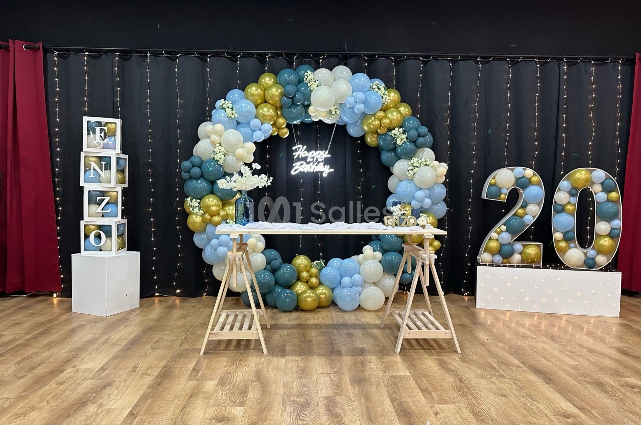 Décoration d'anniversaire avec arche de ballons, table festive, chiffres ’20’ lumineux et guirlandes lumineuses en arrière…