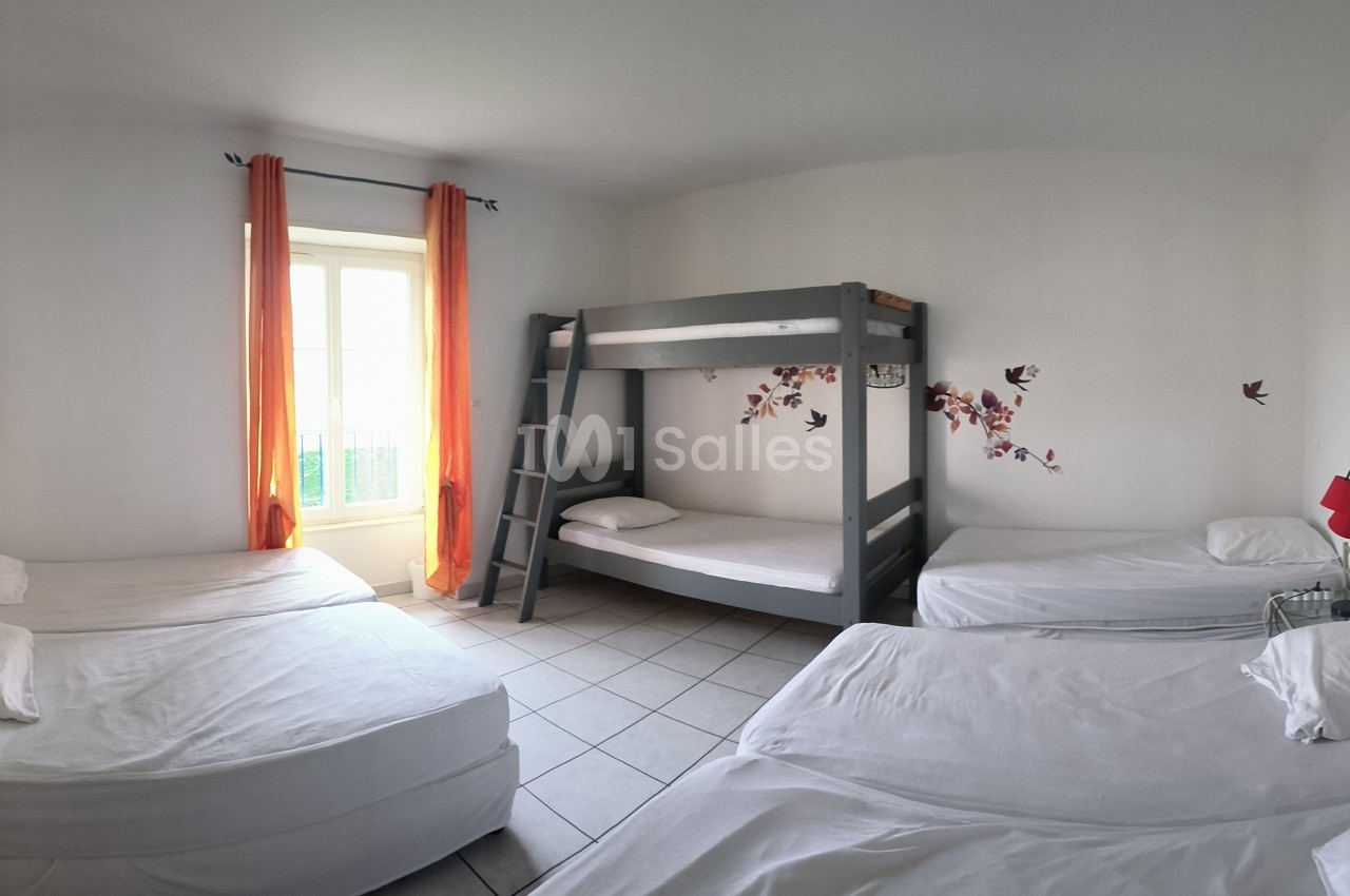 Chambre lumineuse avec lits simples, lits superposés, murs blancs, rideaux orange et décorations murales colorées.