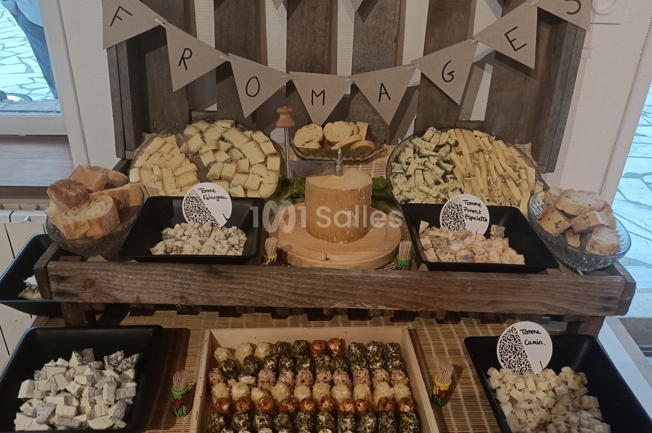 Plateau de dégustation de fromages variés avec morceaux de pain, présenté sur une table en bois décorée.