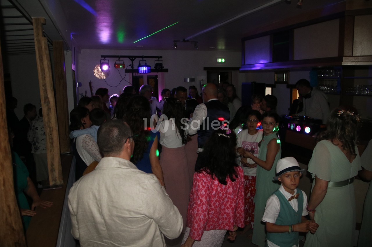 Groupe de personnes dans une salle sombre, éclairée par des lumières colorées, lors d'une fête ou d'un événement.