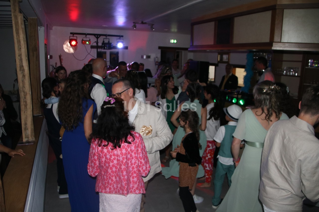 Groupe de personnes dans une salle éclairée par des lumières colorées, discutant et dansant lors d'un événement festif.