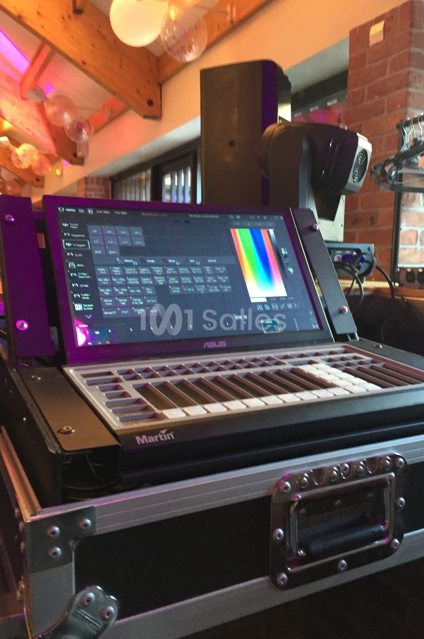Console de contrôle d'éclairage avec écran tactile affichant des réglages colorimétriques, installée dans un espace…