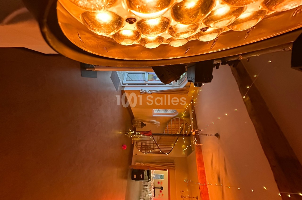 L'intérieur d'une pièce chaleureusement éclairée avec des guirlandes lumineuses et un lustre doré au plafond.