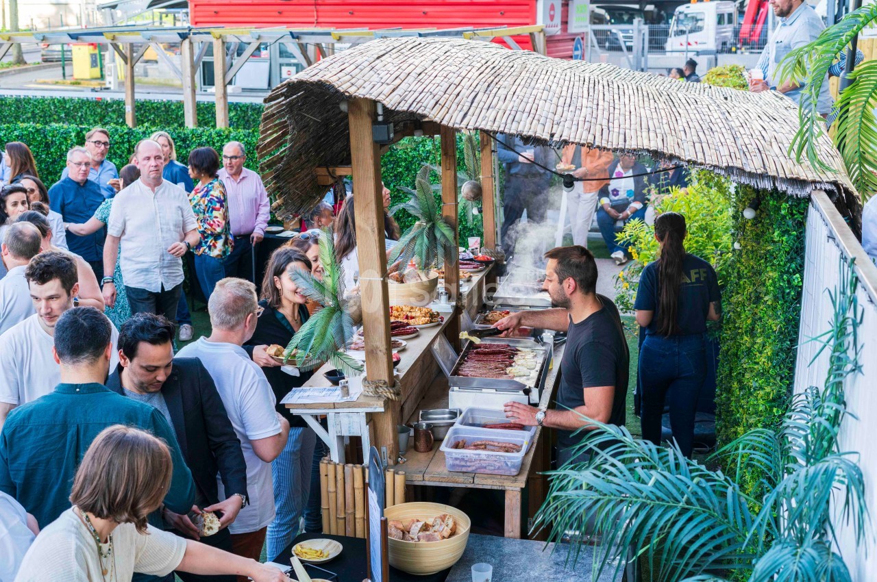 Stand de cuisine en plein air avec un cuisinier préparant des plats, entouré de personnes dans une ambiance conviviale.