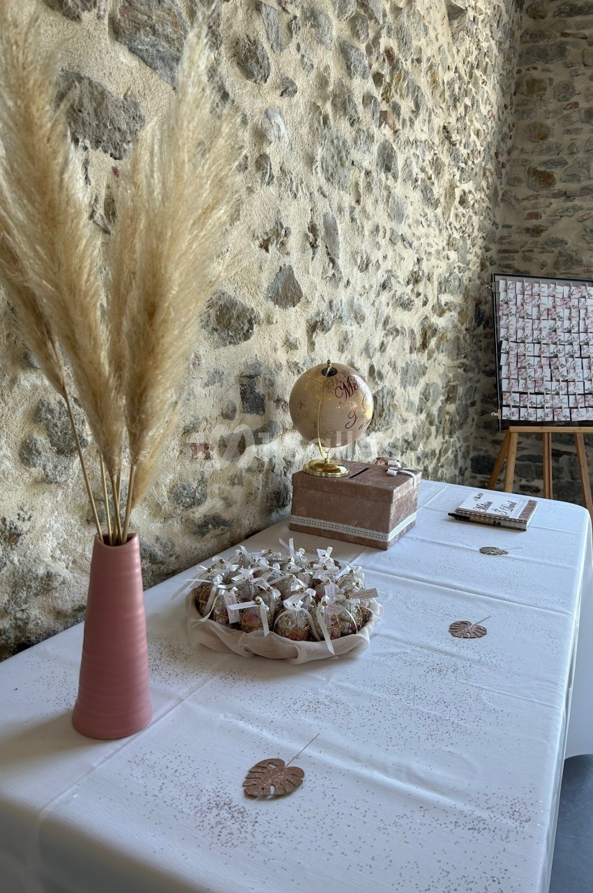 Table décorée avec un vase de pampas, un globe, des cadeaux emballés et un tableau sur chevalet en arrière-plan.