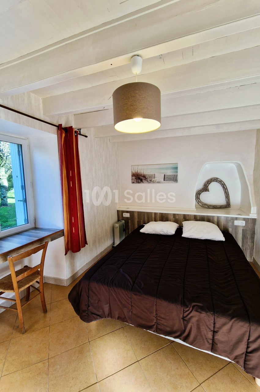 Chambre lumineuse avec lit double, bureau en bois près d'une fenêtre et décoration murale minimaliste.