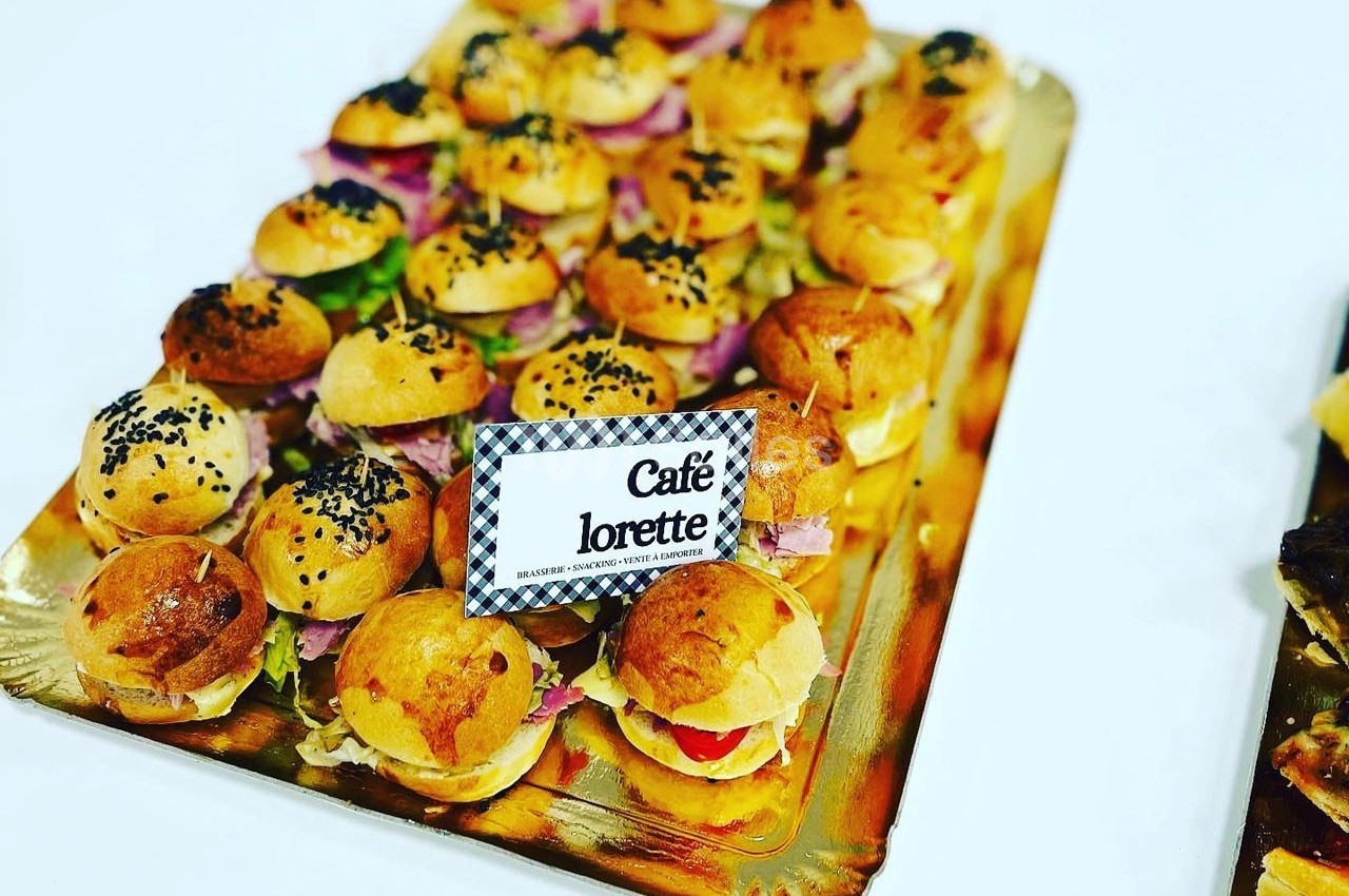 Plateau de mini-burgers variés garnis de légumes et de charcuterie, présenté sur un support doré.