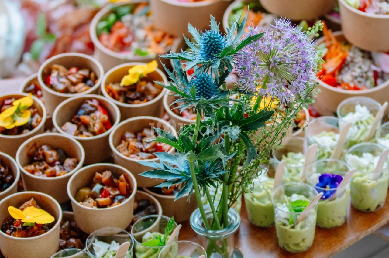 Plats variés présentés dans des contenants individuels avec un bouquet de fleurs en premier plan.