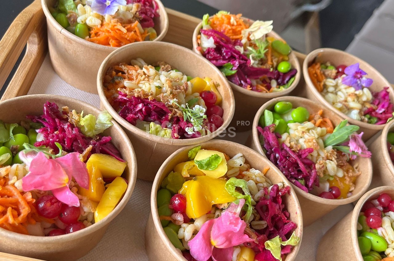 Assortiment de bols en carton contenant des salades colorées garnies de fleurs comestibles et de légumes variés.