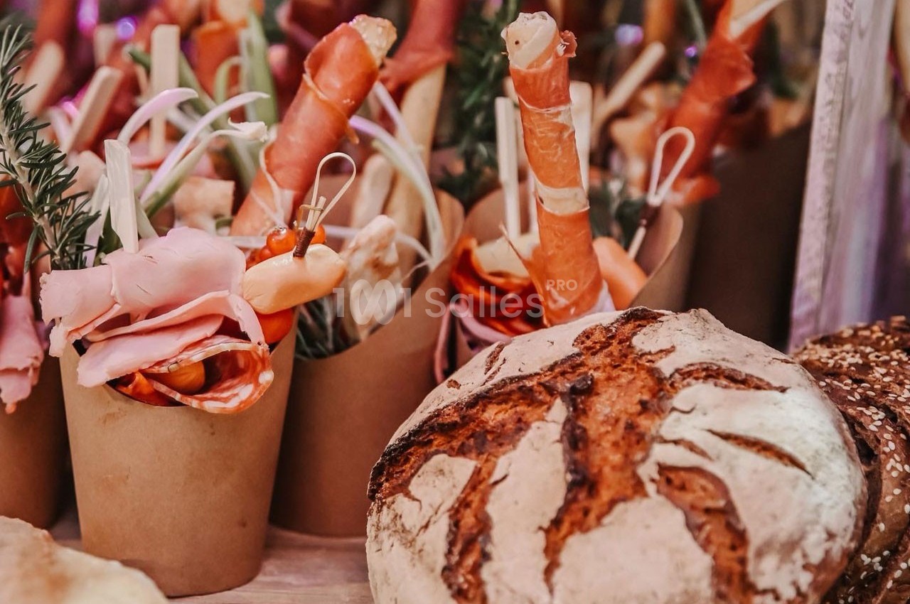 Assortiment de charcuteries et légumes en verrines avec un pain artisanal en premier plan.