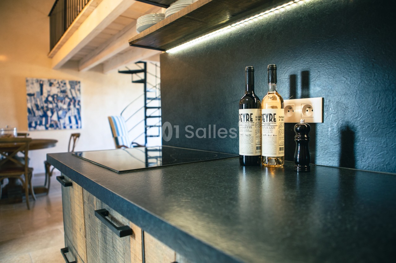 Plan de travail de cuisine moderne avec deux bouteilles de vin, un moulin à poivre et une plaque de cuisson intégrée.