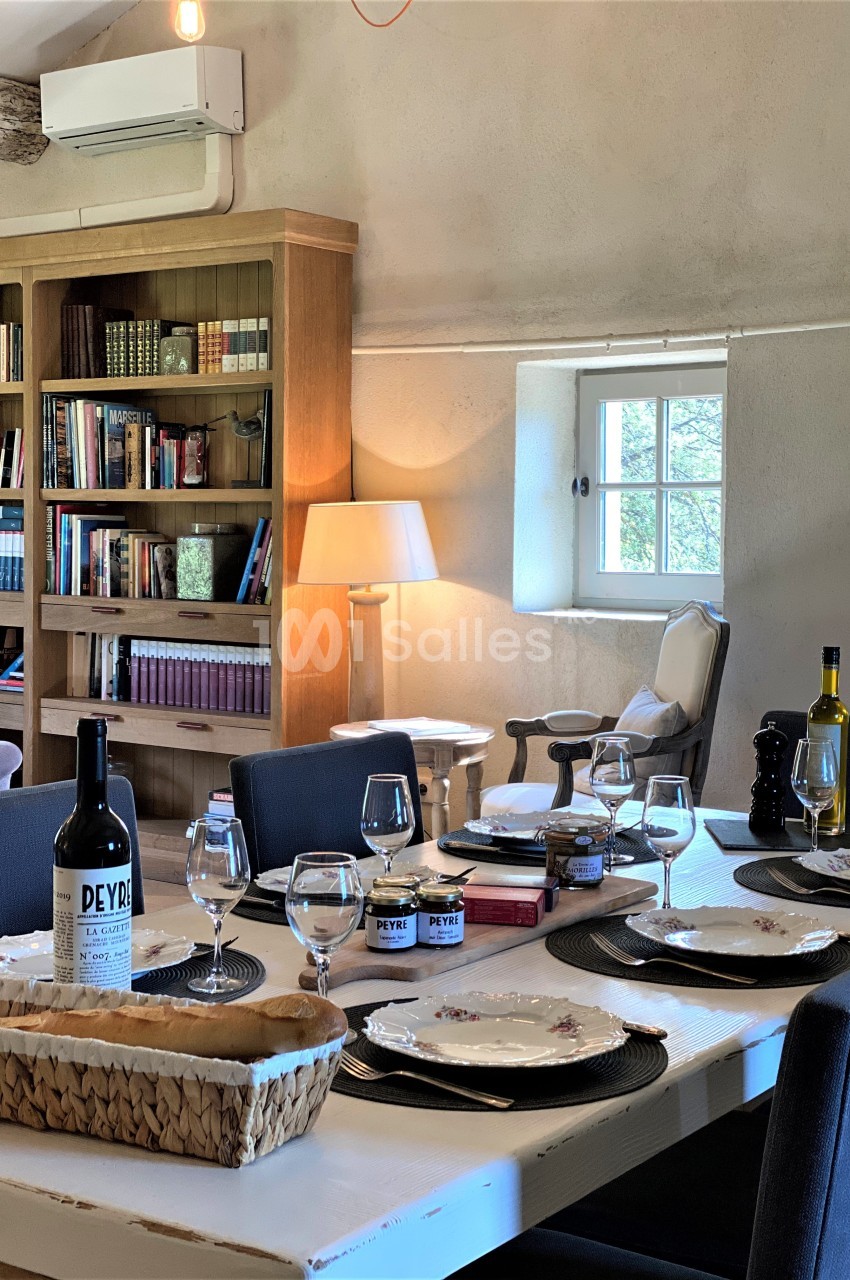 Table dressée dans une salle lumineuse avec bibliothèque en bois, lampadaire et fenêtre donnant sur l'extérieur.