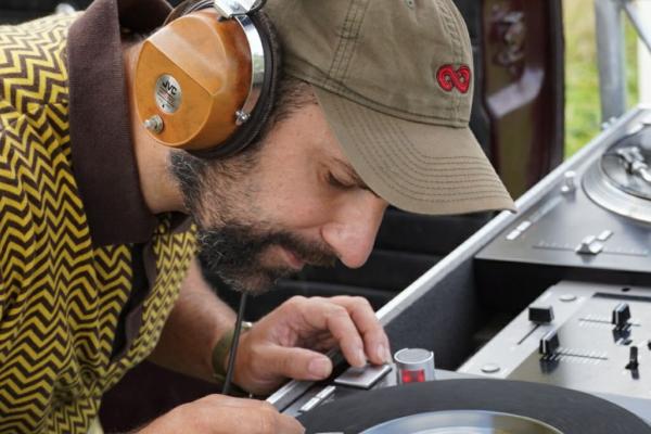 Un homme portant un casque audio écoute attentivement un disque vinyle sur une platine.