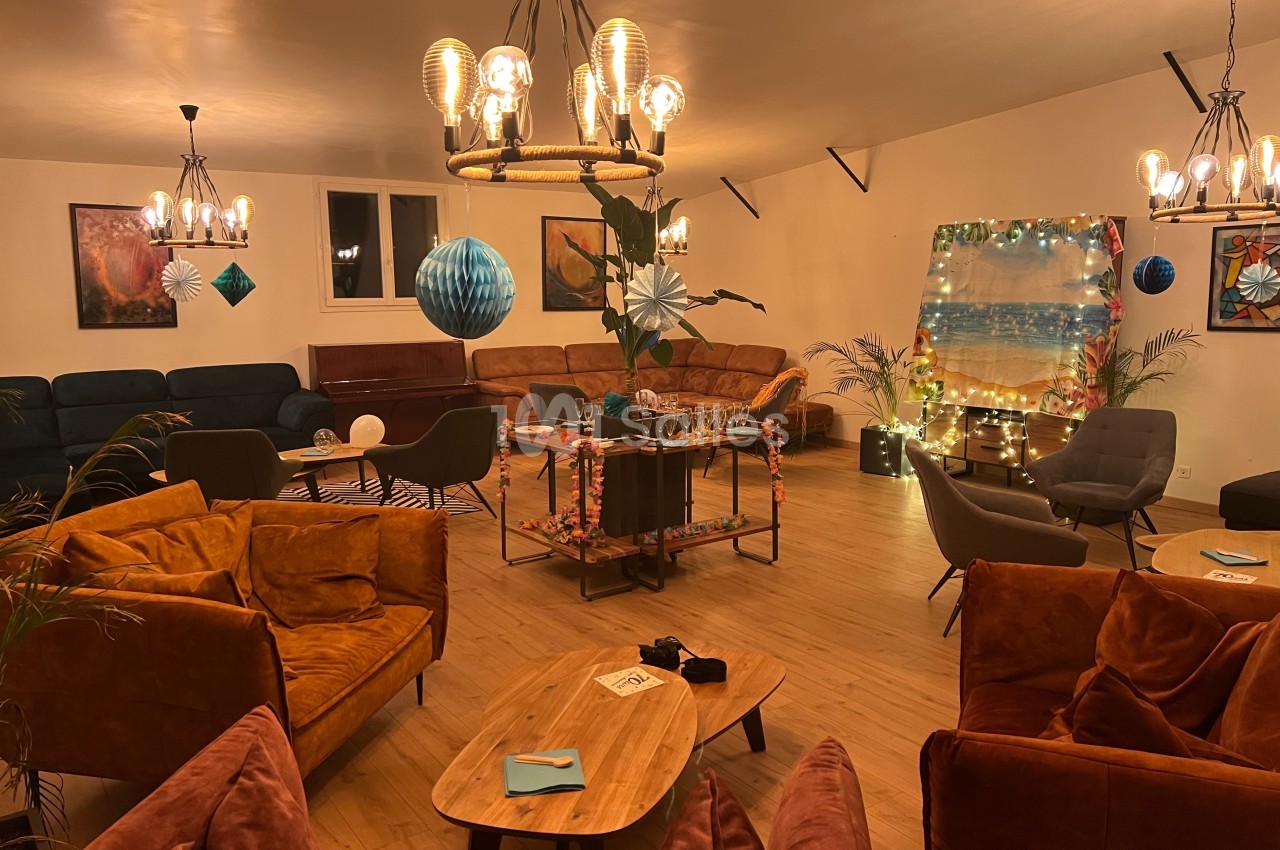 Salle conviviale décorée pour un événement, avec canapés, tables basses, guirlandes lumineuses et ornements festifs.