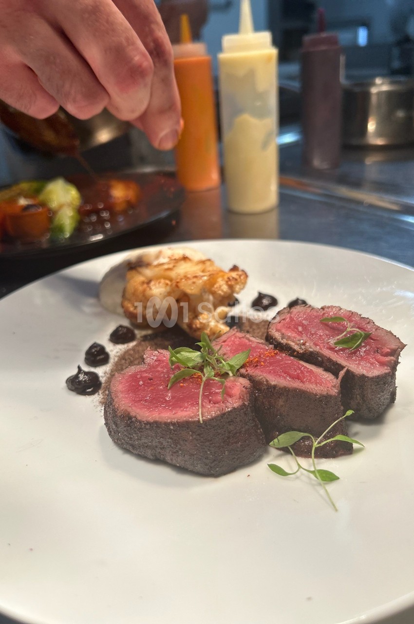 Assiette gastronomique avec filet de viande saignante, purée, chou-fleur rôti et sauce, dressée dans une cuisine…
