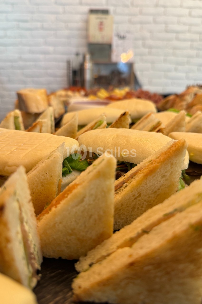 Assortiment de sandwichs triangulaires garnis, disposés sur un plateau dans un cadre lumineux.