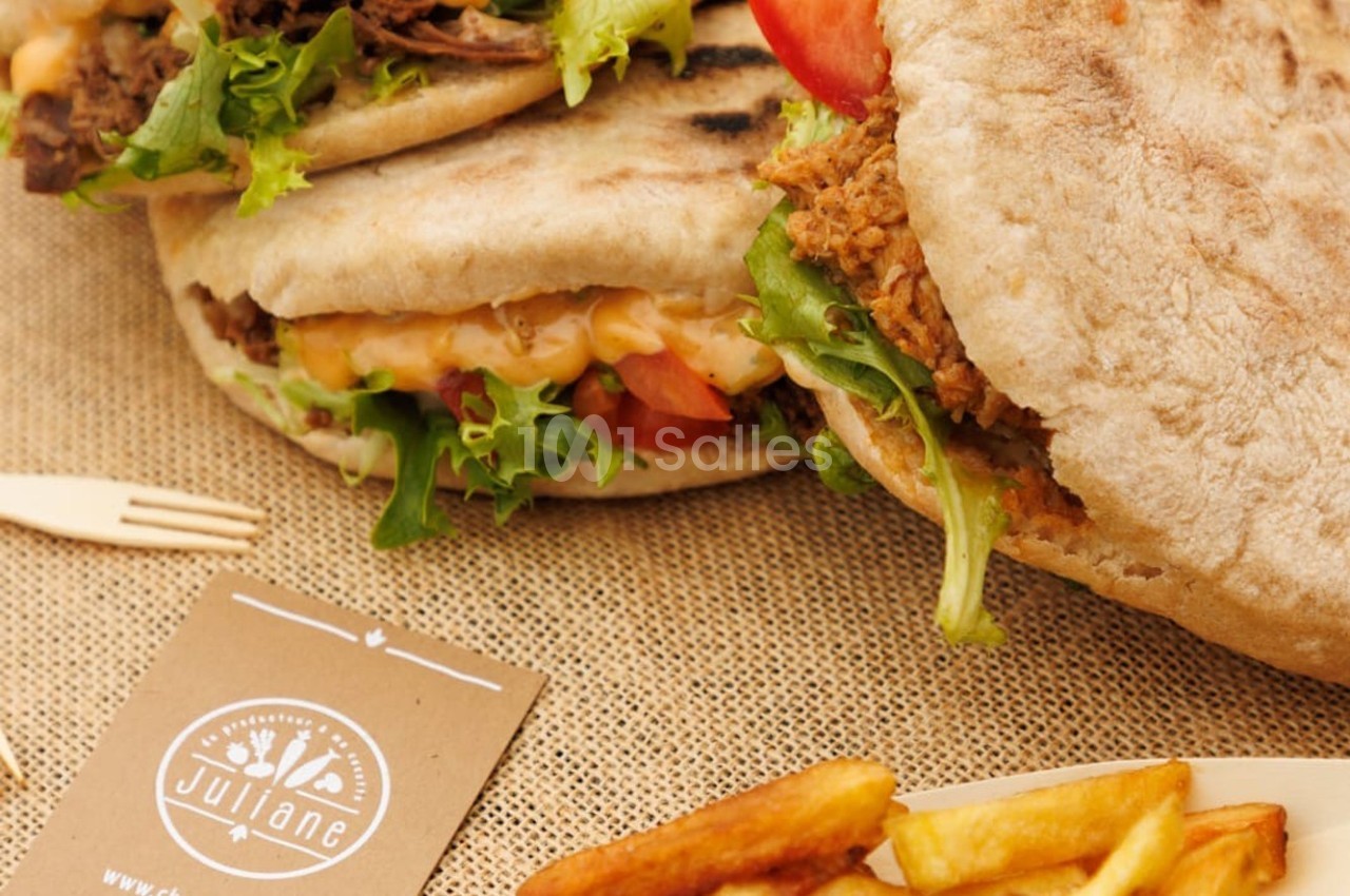 Pains garnis de légumes, viande et sauce, accompagnés de frites sur une nappe en toile beige.