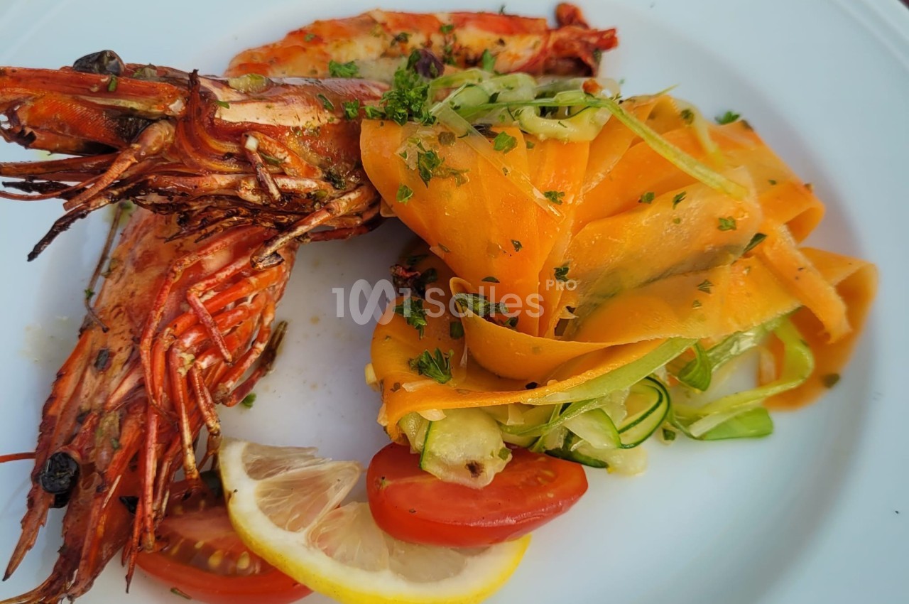 Assiette avec crevettes grillées, tagliatelles de légumes, quartiers de citron et tomates cerises.