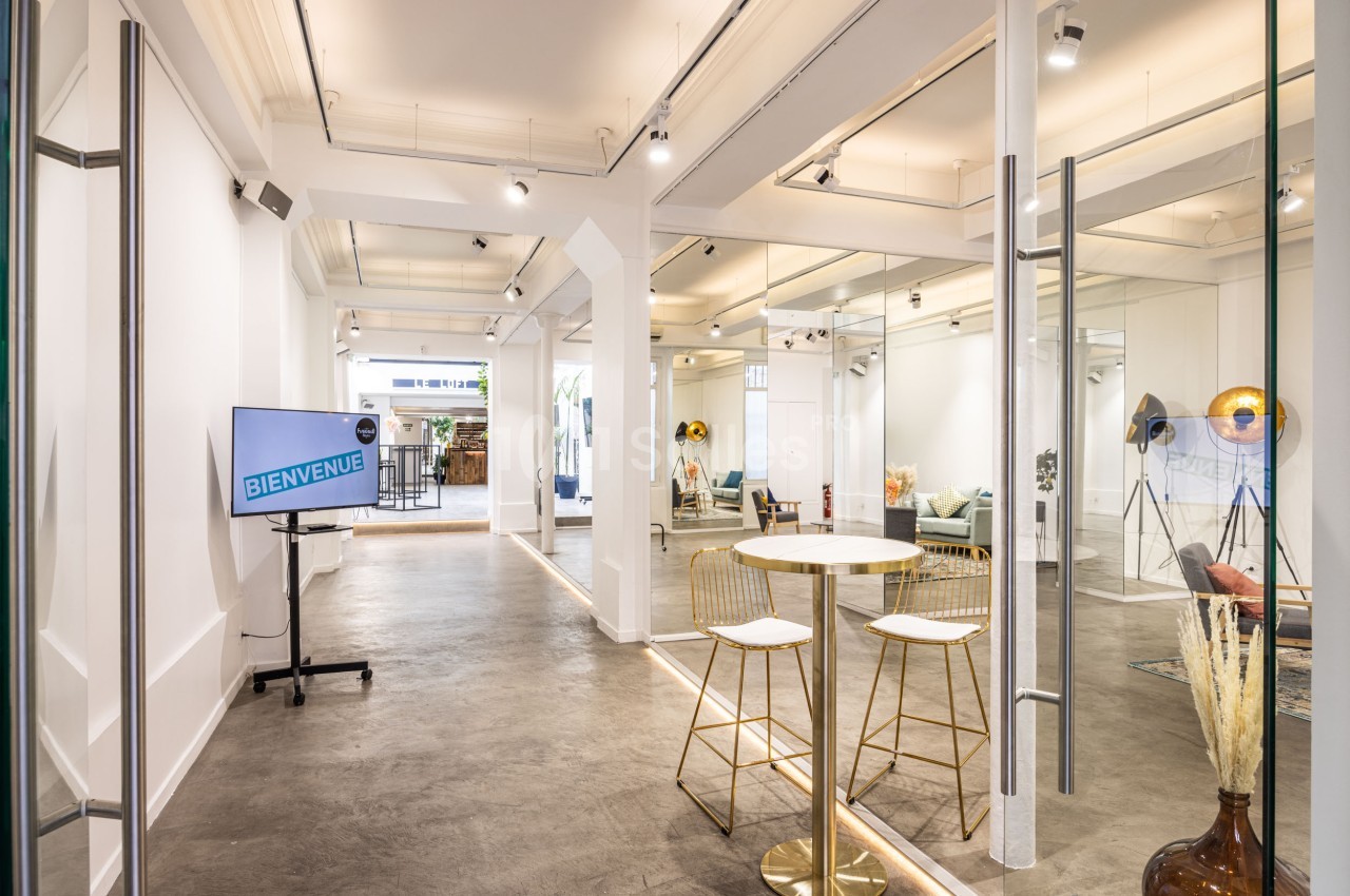 Espace lumineux avec murs blancs, mobilier minimaliste, écran affichant ’Bienvenue’ et décorations modernes.