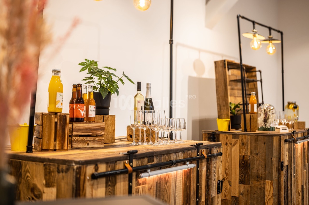 Comptoirs en bois avec bouteilles, verres et décorations végétales dans un espace lumineux.