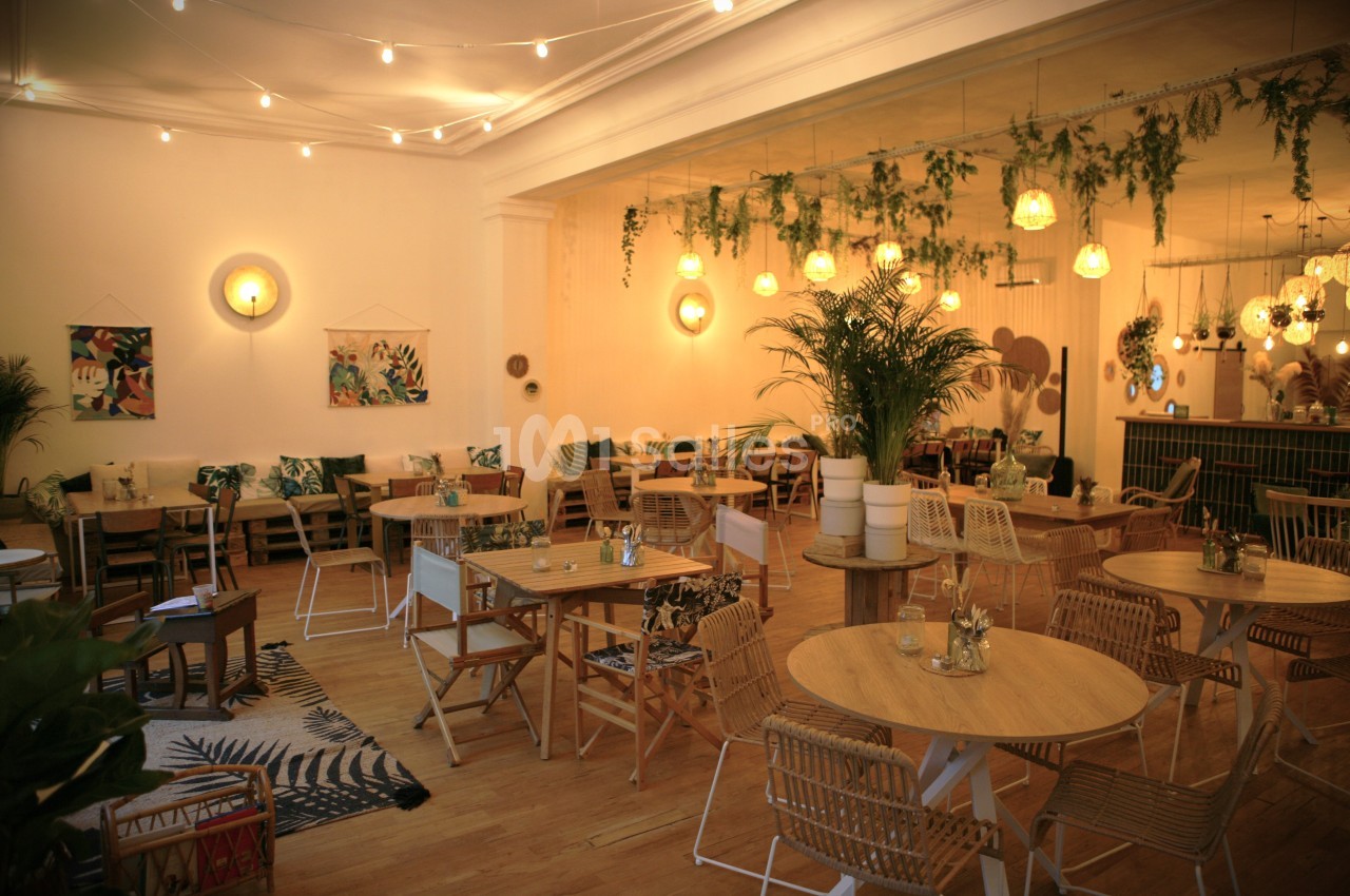 Salle de restaurant lumineuse avec décoration végétale, mobilier en bois clair et ambiance chaleureuse.