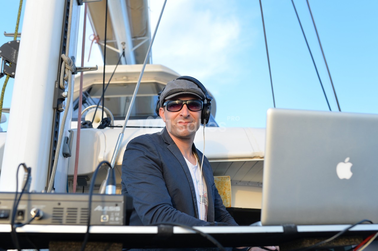 Un homme portant un casque audio travaille sur un ordinateur portable à bord d'un bateau sous un ciel dégagé.