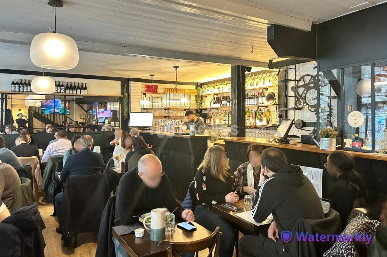 Intérieur d'un café animé avec des clients attablés et un comptoir en arrière-plan.