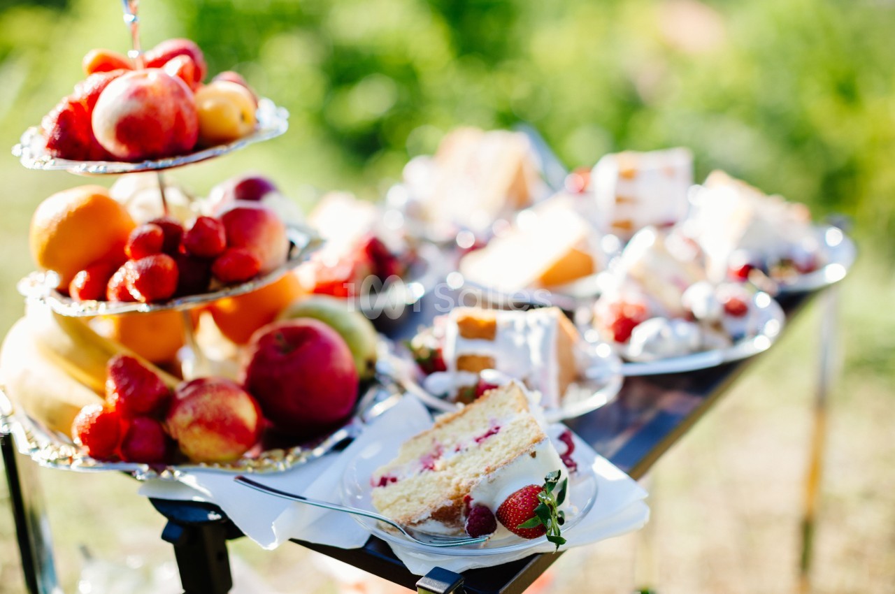 Plateau de fruits frais et assiettes de desserts variés disposés sur une table en extérieur.