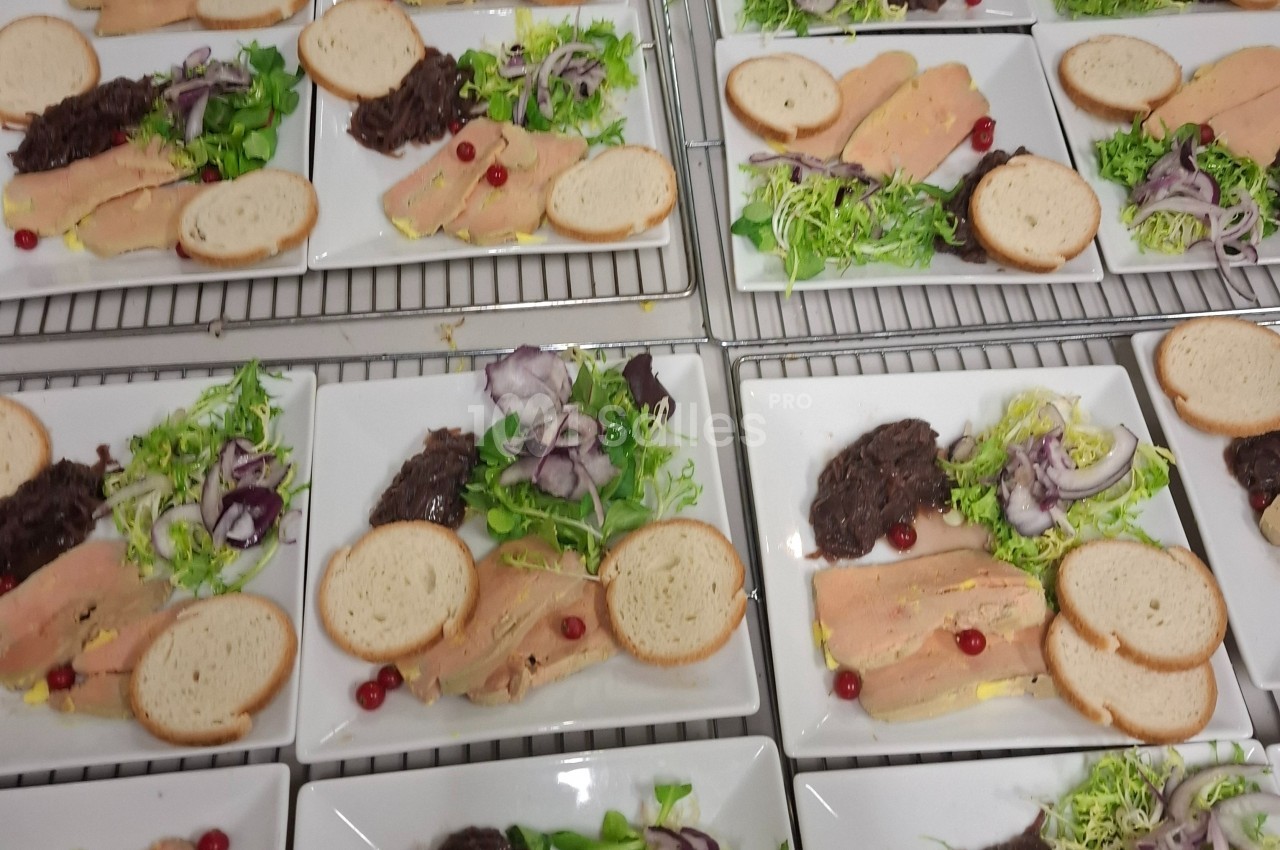 Assiettes dressées avec foie gras, pain, salade verte, confit d'oignons et airelles rouges, alignées sur une grille.