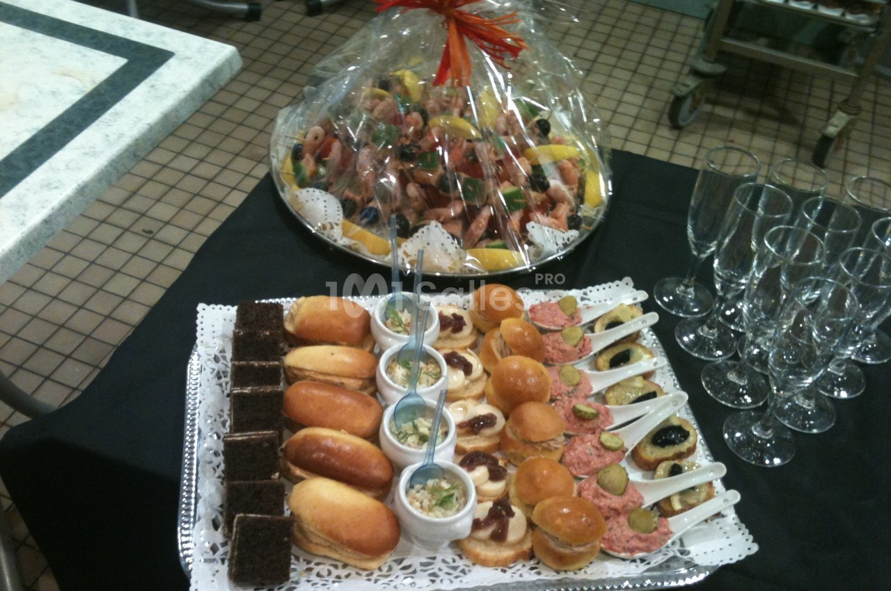 Plateau de mignardises salées et sucrées accompagné de coupes en verre, avec un panier garni en arrière-plan.