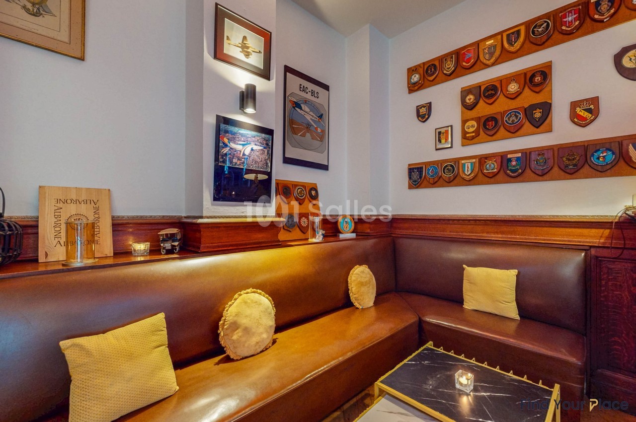 Banquette en cuir brun entourée de murs décorés de plaques et d'insignes militaires dans un espace chaleureux.