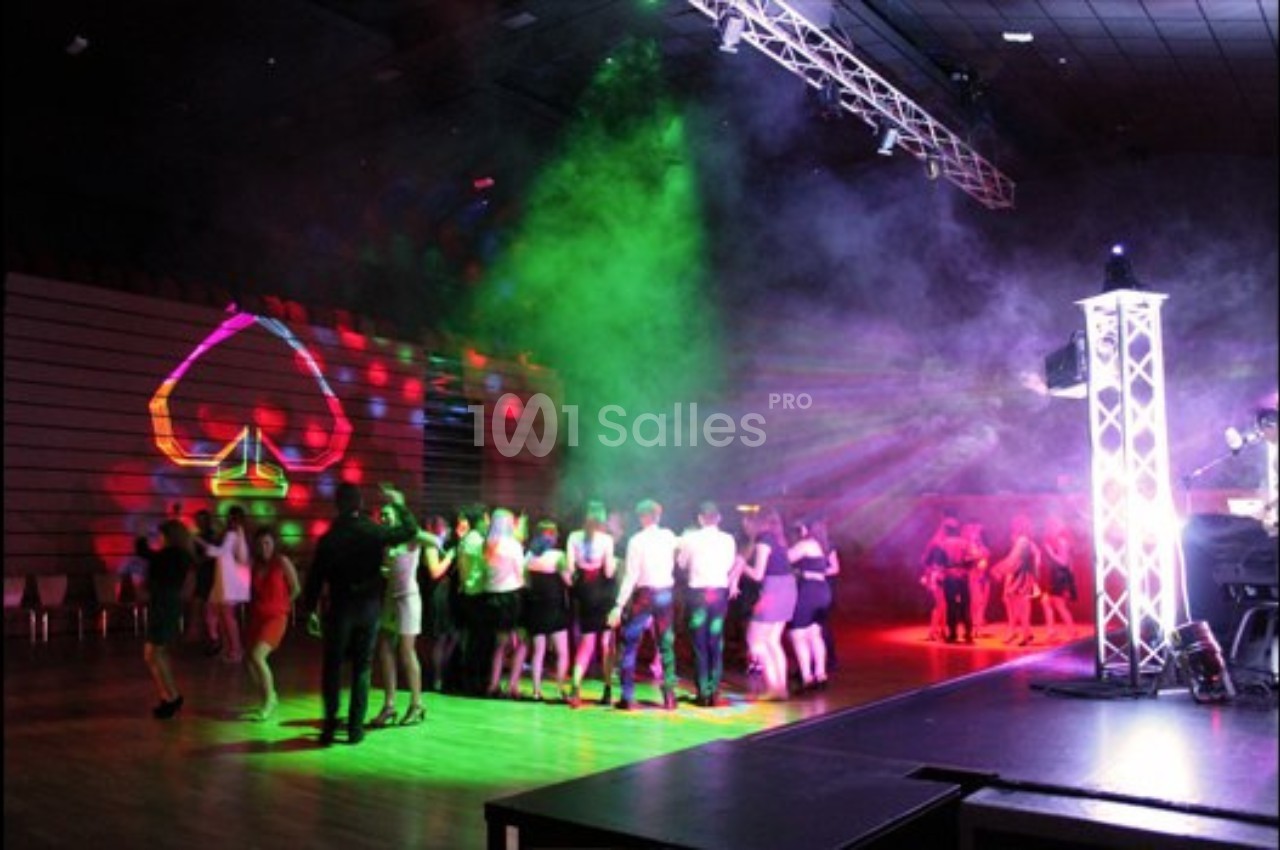 Groupe de personnes dansant dans une salle sombre avec des lumières colorées et des projections lumineuses.