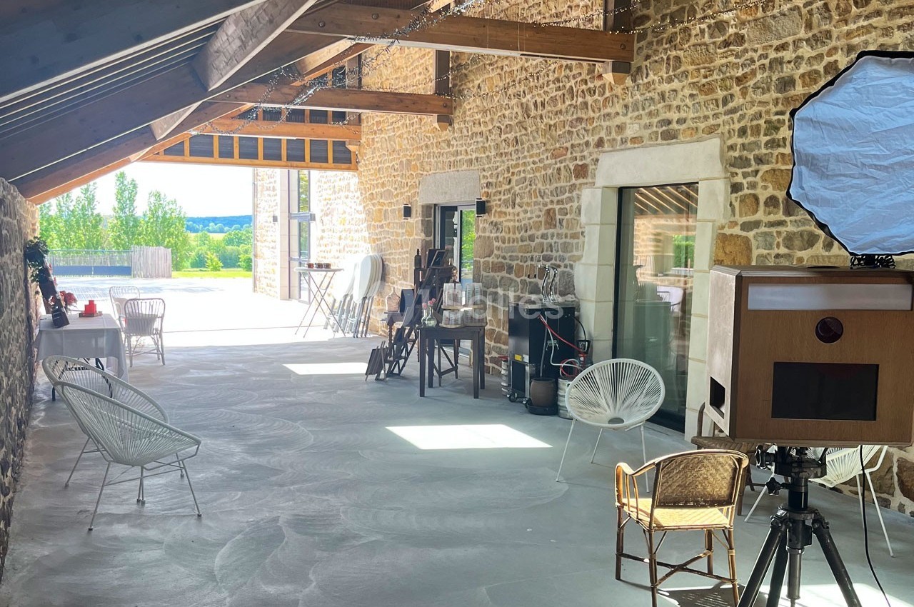 Espace lumineux avec murs en pierre, mobilier en rotin et équipement photo installé dans une grande salle ouverte.