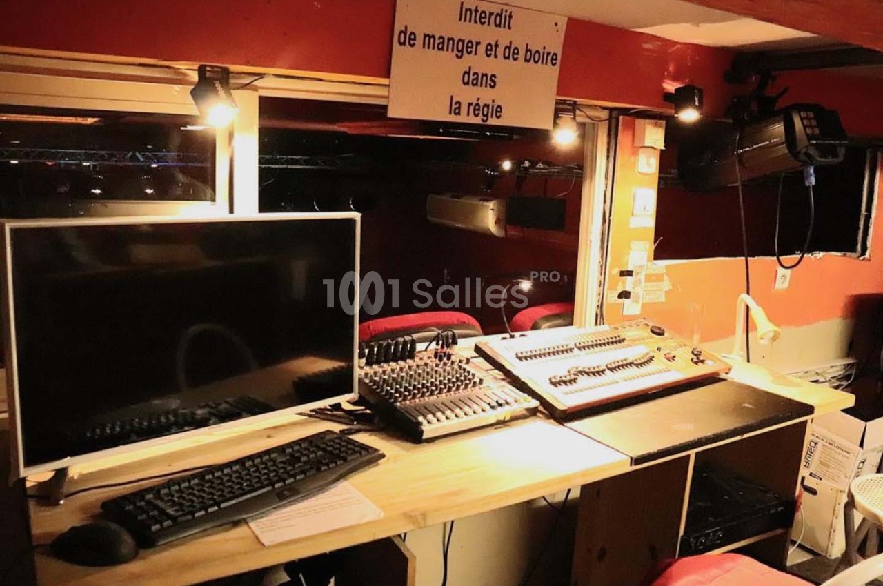 Poste de régie avec écran, clavier, table de mixage et panneau ’Interdit de manger et de boire dans la régie’.