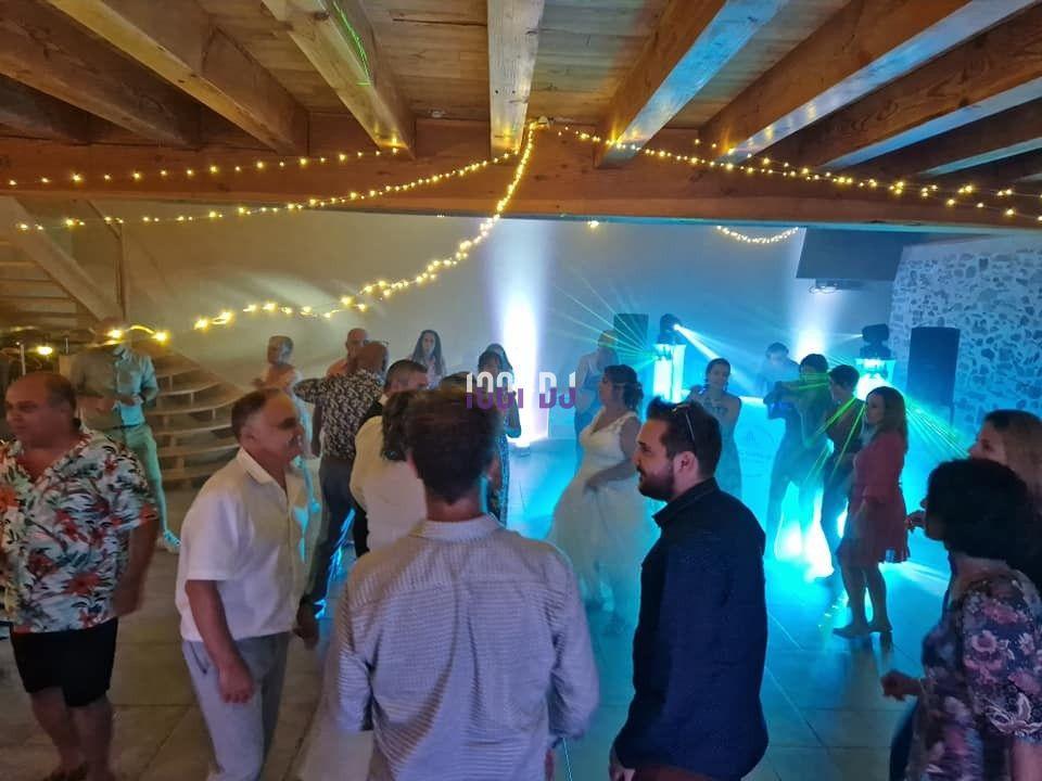 Des personnes dansent dans une salle éclairée par des lumières colorées, avec des guirlandes lumineuses au plafond.
