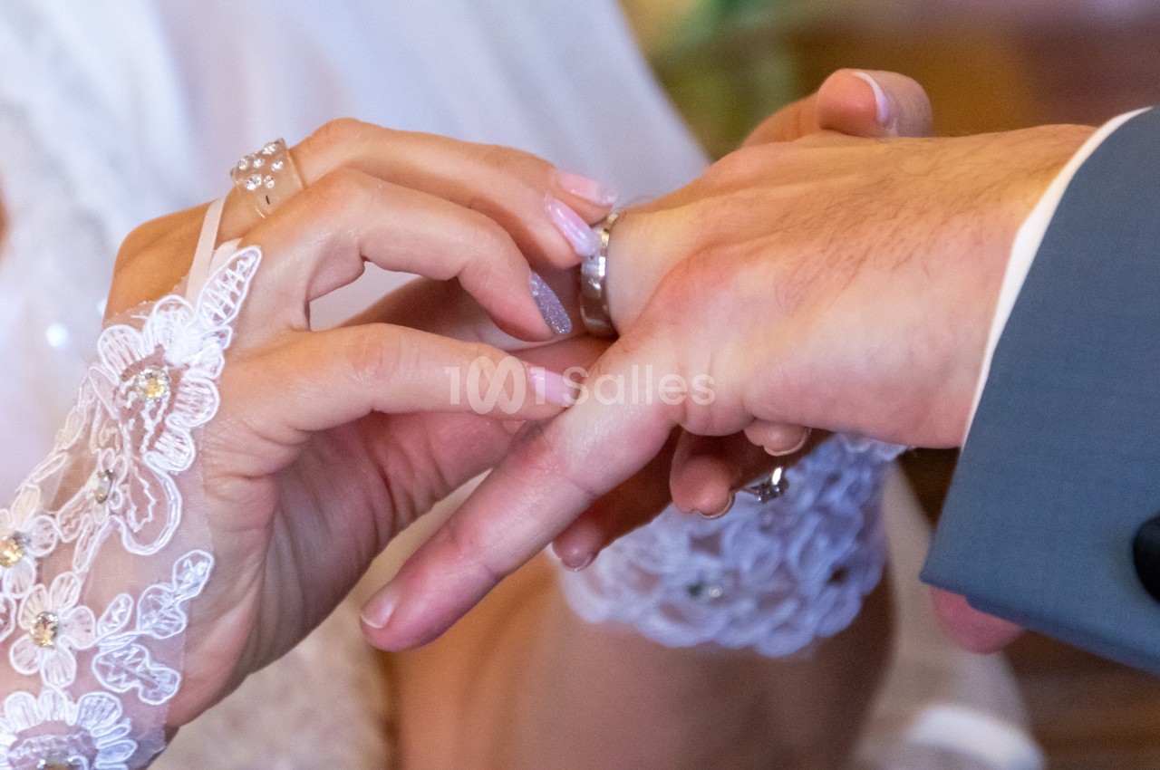 Une mariée glisse une alliance au doigt de son partenaire lors d'une cérémonie de mariage.