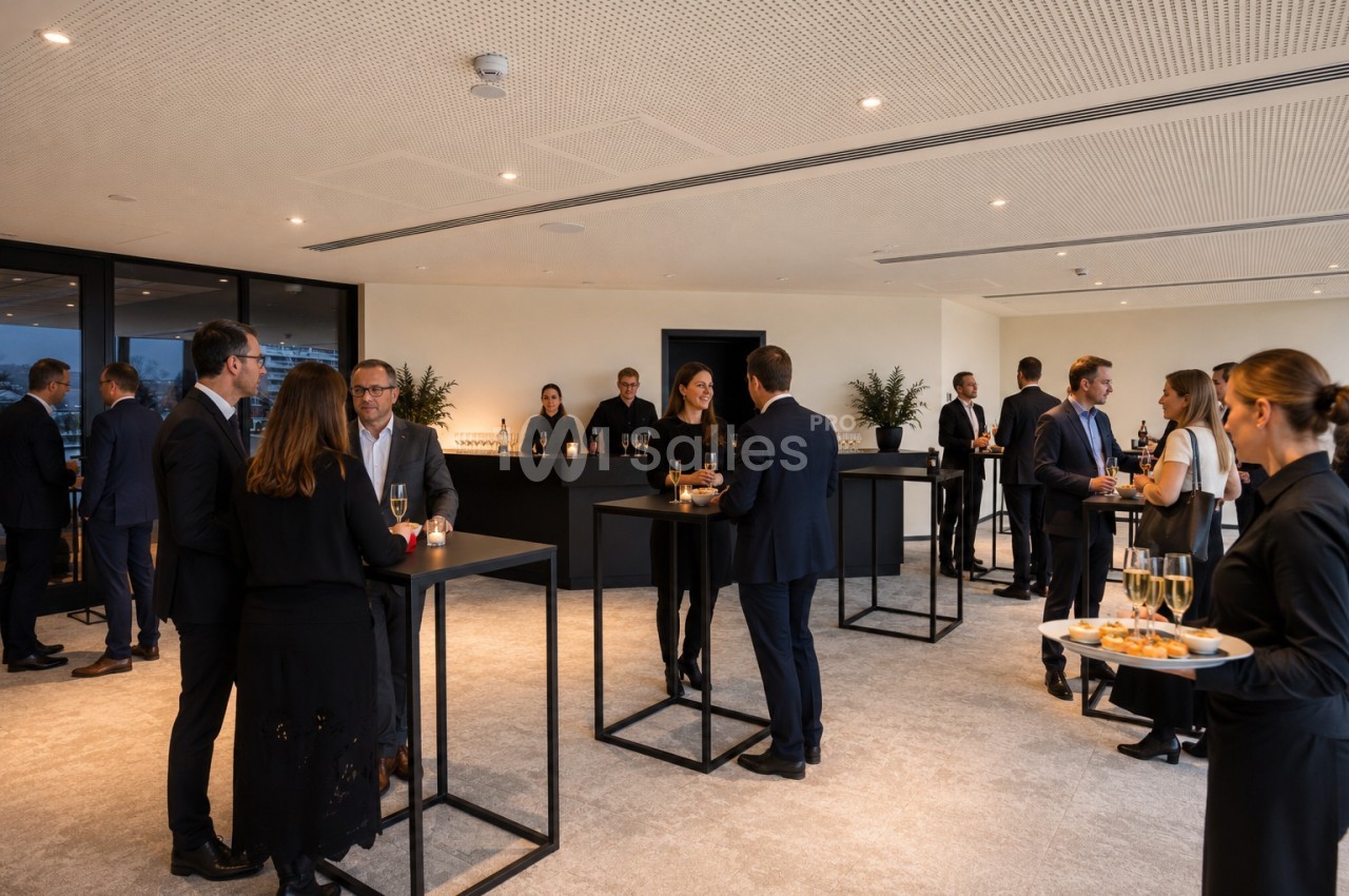 Personnes en tenue professionnelle discutant debout autour de tables hautes dans une salle lumineuse avec un service de…