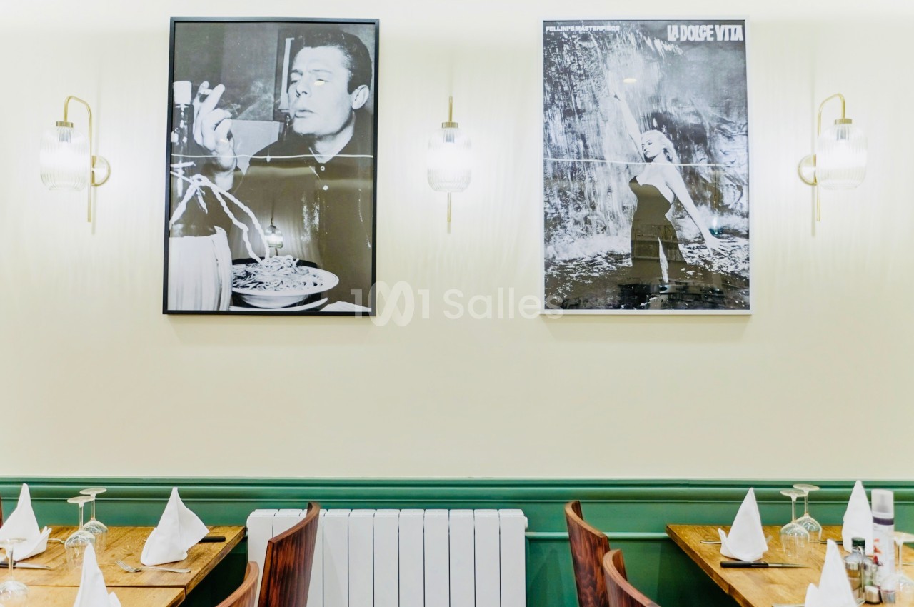 Deux affiches en noir et blanc décorent un mur au-dessus de tables dressées dans un restaurant.