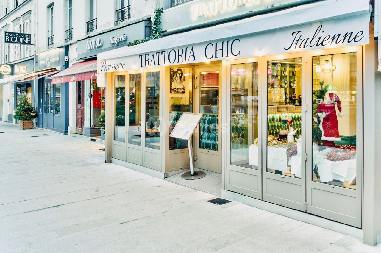 Façade d'un restaurant italien avec vitrines éclairées, menu extérieur et décorations de Noël sur le trottoir.