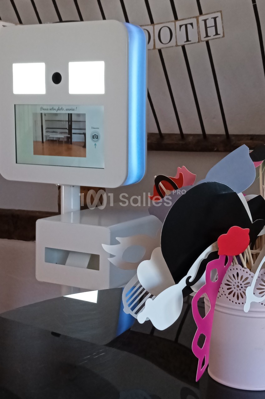 Borne photo interactive avec accessoires colorés disposés dans un pot sur une table, décor en arrière-plan.