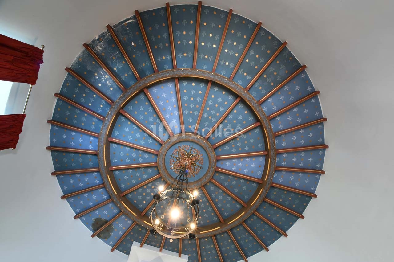 Plafond voûté bleu orné d'étoiles dorées, avec une suspension centrale et des poutres en bois rayonnantes.