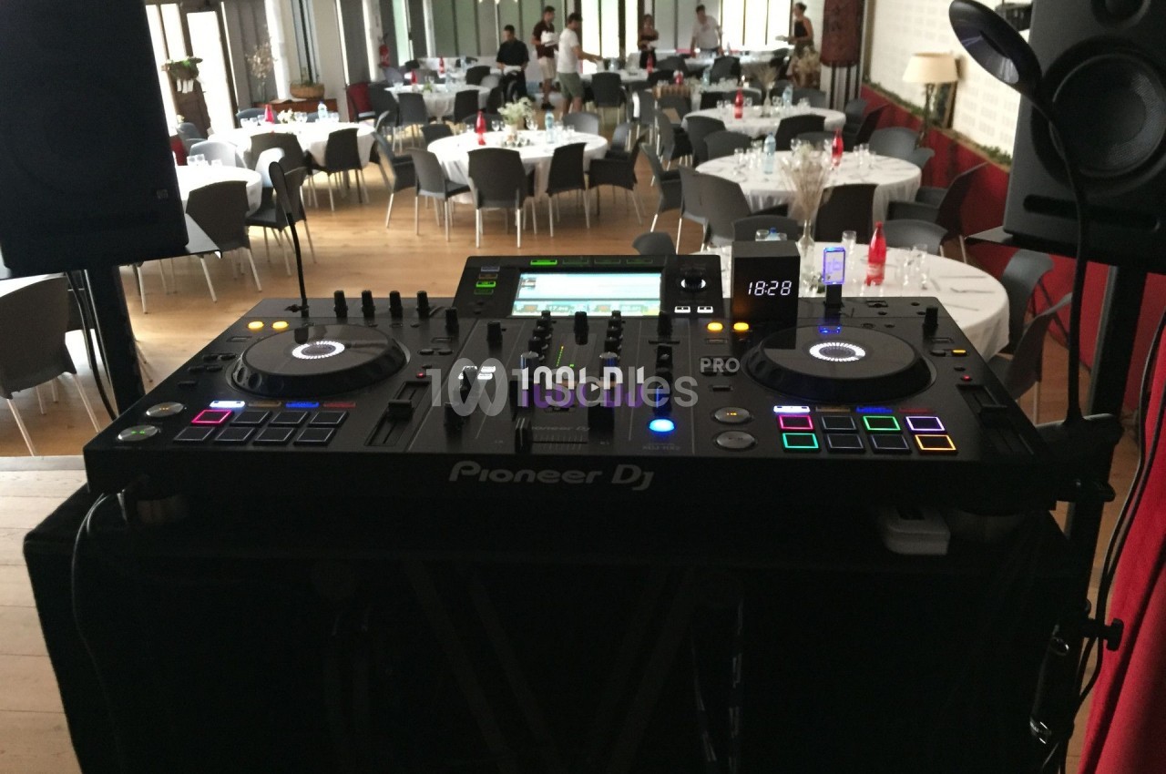 Console DJ Pioneer installée dans une salle de réception avec tables dressées en arrière-plan.