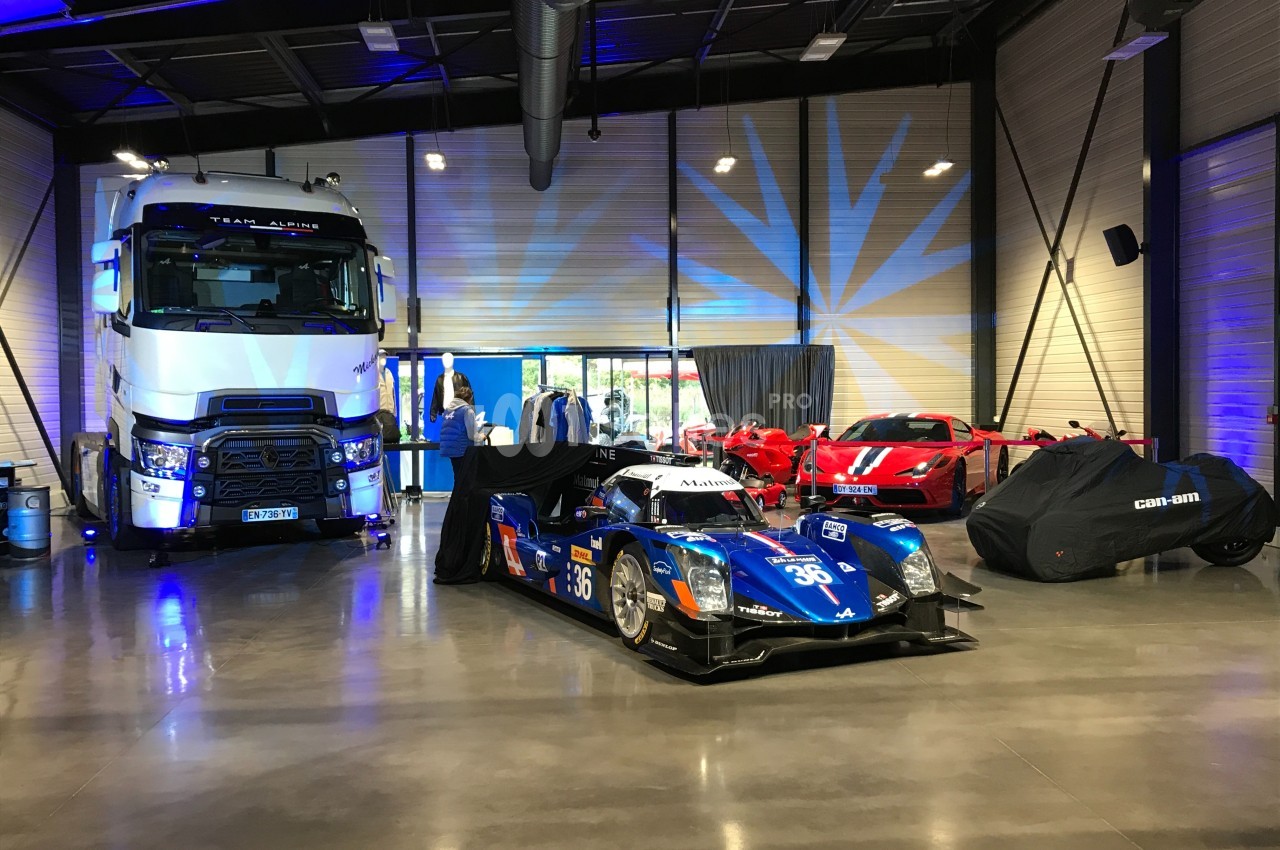 Voitures de sport, camion et véhicules couverts exposés dans un espace intérieur moderne avec éclairage bleu.